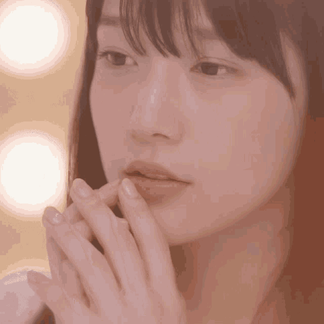 a close up of a woman 's face with her hand on her mouth