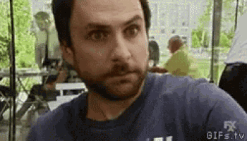 a man with a beard wearing a blue shirt is sitting at a table in a restaurant .