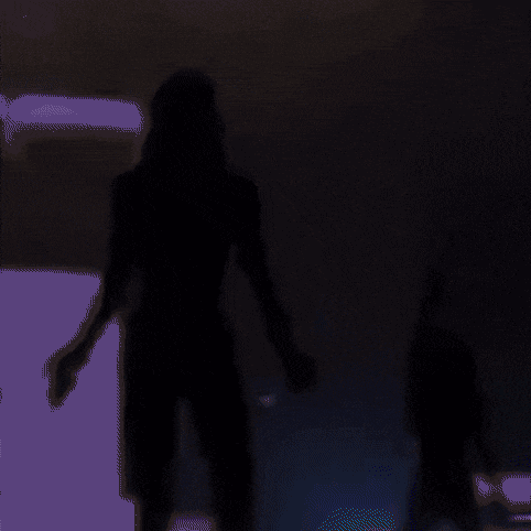 a silhouette of a woman with her arms outstretched in a dark room .