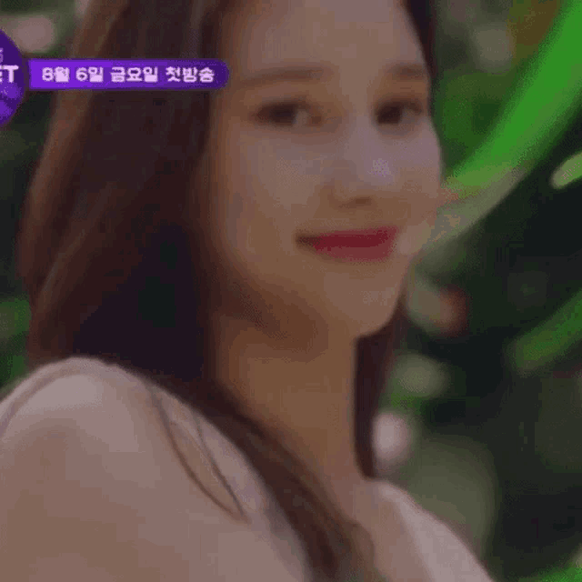 a close up of a woman 's face with a green background and a purple sign in the background .