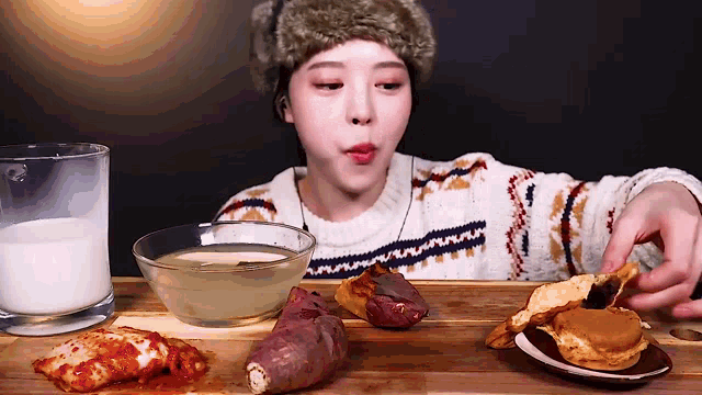 a woman is sitting at a table with a bowl of milk and a plate of food
