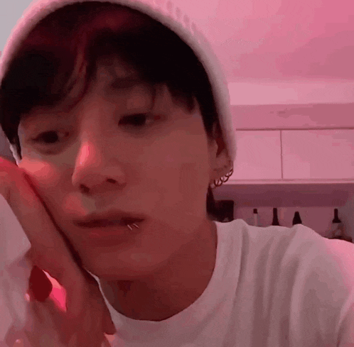 a young man with a piercing in his lip is wearing a white beanie and a white shirt .