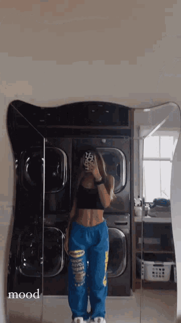 a woman is taking a picture of herself in front of a stack of washers and dryers .