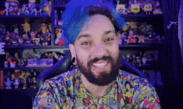 a man with blue hair and a beard is smiling in front of a toy shelf .