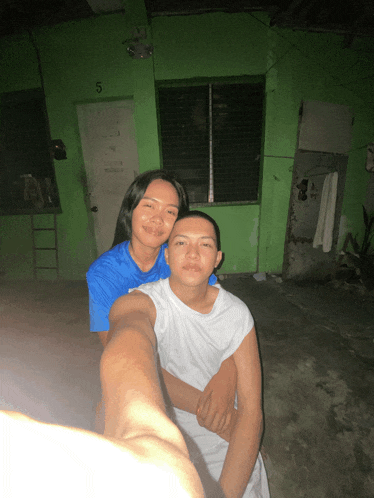 a woman in a blue shirt is hugging a man in a white shirt