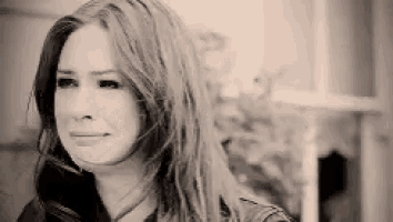 a black and white photo of a woman with long hair crying .