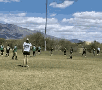 a group of people are playing a game of soccer on a field with mountains in the background .