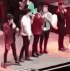 a group of people are standing on a stage and dancing .