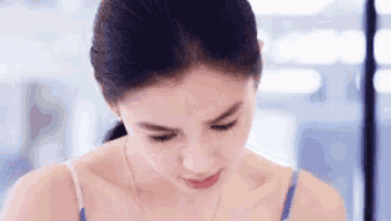 a close up of a woman 's face with a ponytail looking down .
