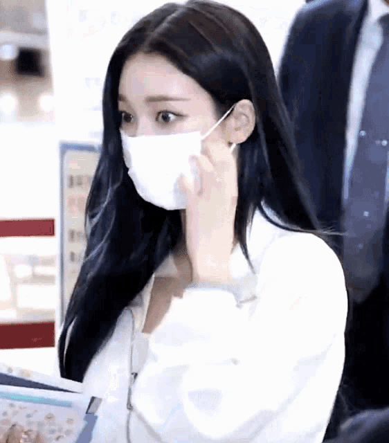 a woman wearing a white face mask is looking at something