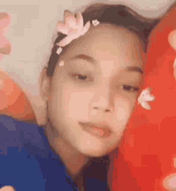 a girl with a flower in her hair is laying on a red pillow .