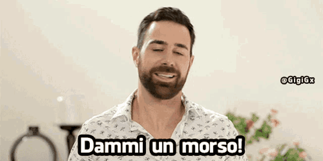 a man with a beard and a white shirt says dammi un morso