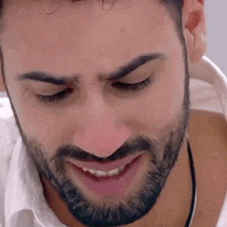 a close up of a man 's face with a beard and a white shirt .