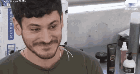 a man with a beard is smiling while sitting in front of a box that says sheets x x 24 .