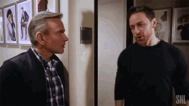 two men are standing next to each other in a room with snl written on the bottom right