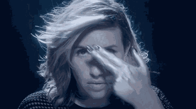 a woman with long hair is covering her face with her hand