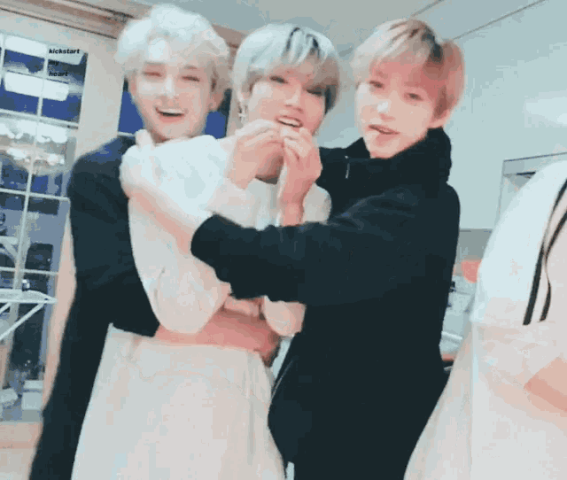three young men are hugging each other in a room with kickstart written on the bottom