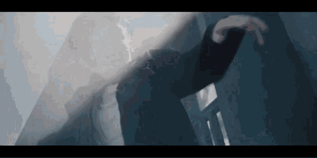 a man in a suit is standing in a dark room with his hands outstretched .