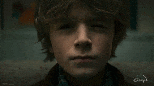 a close up of a young boy 's face with a disney + logo behind him