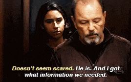 a man and a girl are standing next to each other in a dark room . the man is talking to the girl .