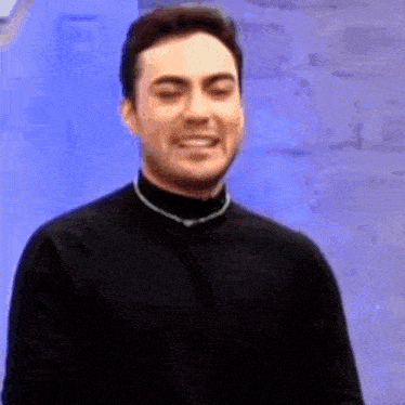 a man in a black shirt is making a funny face while pointing at the camera .