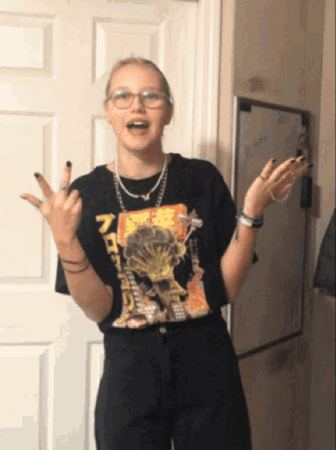 a girl wearing glasses and a black shirt with chinese writing on it is giving the middle finger