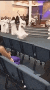 a group of people are dancing in a church while people sit in the chairs .