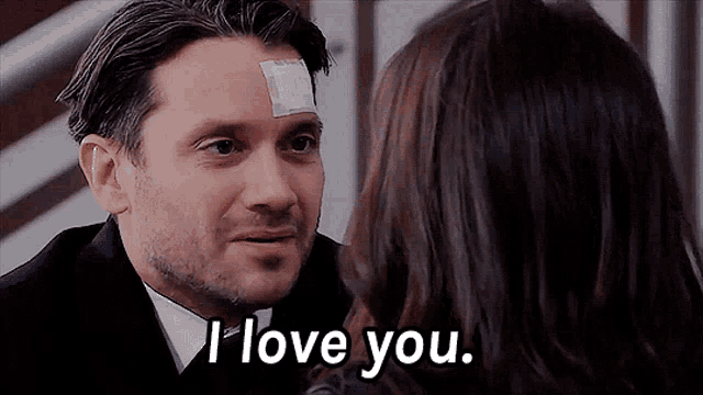 a man with a bandage on his forehead is talking to a woman who says i love you .