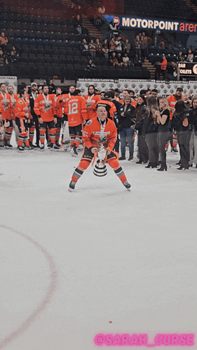 a hockey player holds up a puck in front of a motorpoint arena banner