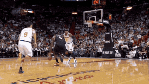 a basketball game is being played in front of a big nba tv ad