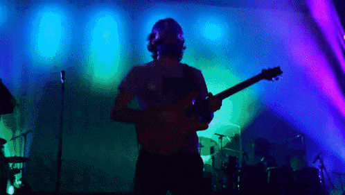a man is playing a guitar in front of a blue and purple background