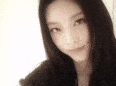 a close up of a woman 's face with long black hair looking at the camera .