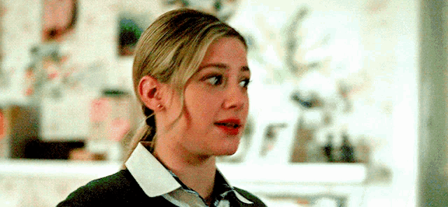 a close up of a woman 's face with a ponytail and a tie .