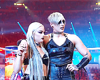 two women are standing next to each other in a ring with a pepsi logo on the wall behind them