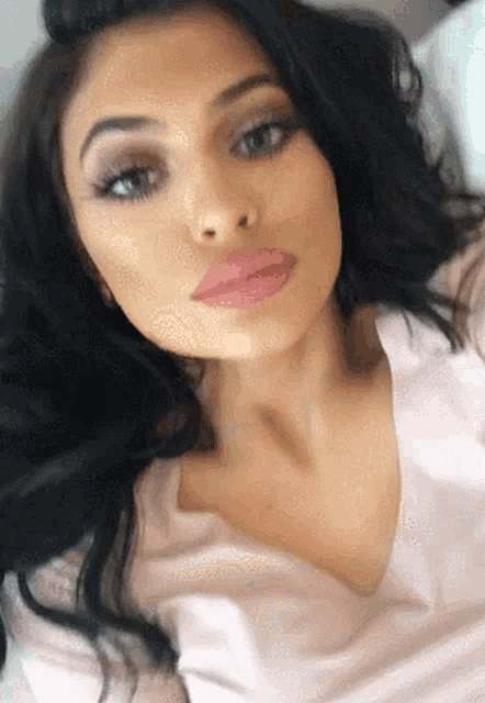 a close up of a woman taking a selfie with her eyes closed and her hair in a bun .