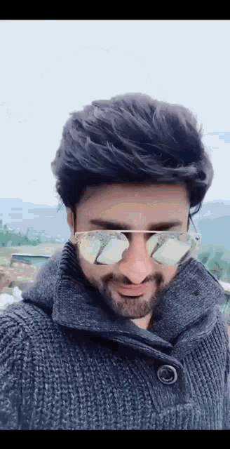 a man with a beard wearing sunglasses and a grey sweater