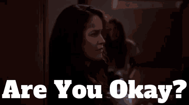 a woman in a dark room with the words are you okay behind her