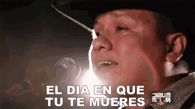 a man singing into a microphone with the words el dia en que tu te mueres behind him