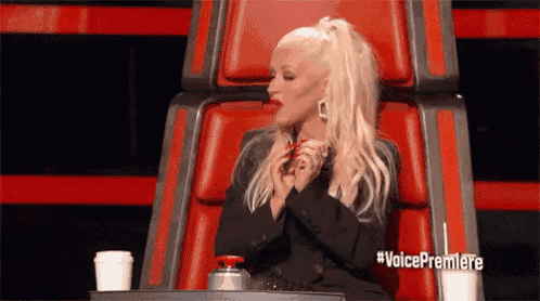 a woman is sitting in a red chair with a cup of coffee and the words voice premiere on the bottom