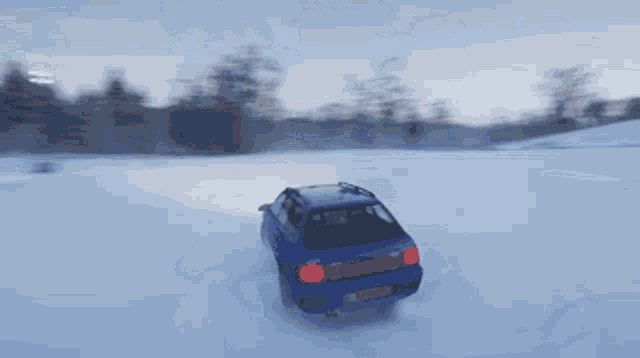 a blue car is driving through a snow covered field