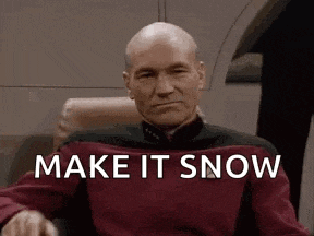 a man in a red shirt is sitting in a chair with the words `` make it snow '' written on his face .