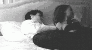 a man and a woman are sitting on a bed looking at each other .