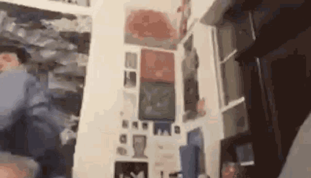 a blurry picture of a person standing in a room with a lot of posters on the wall .