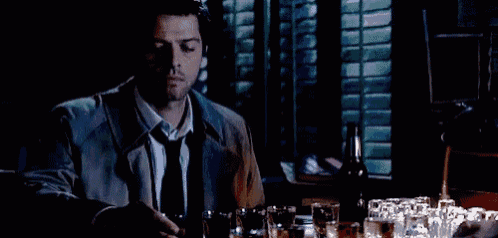 a man in a suit and tie is drinking from a shot glass in a bar .