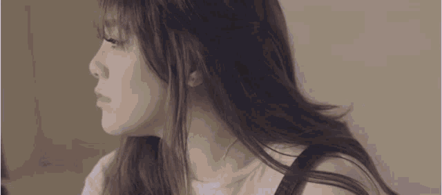 a woman with long brown hair is wearing a white shirt and black overalls