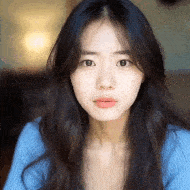 a young woman with long dark hair is wearing a blue sweater .