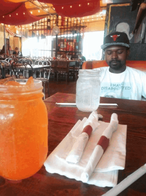 a man wearing a t-shirt that says i have disappointed sits at a restaurant table