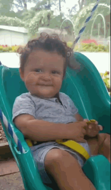 a baby is smiling while sitting on a green slide