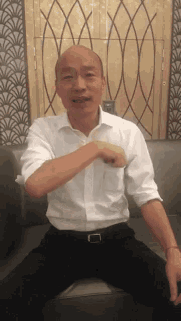 a man in a white shirt is sitting on a couch