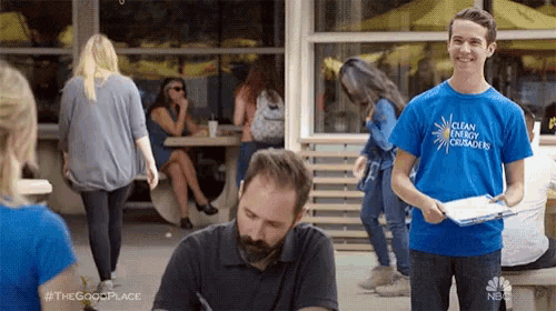 a man wearing a blue shirt that says clean energy conscious is standing next to another man .